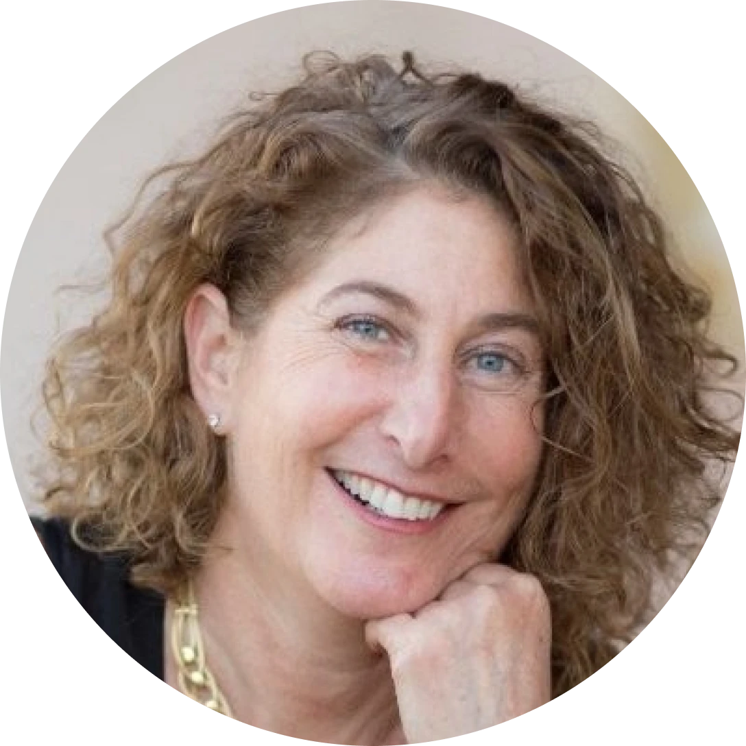 smiling woman with curly light brown hair resting her chin on her hand in a head and shoulders portrait of a friendly smile